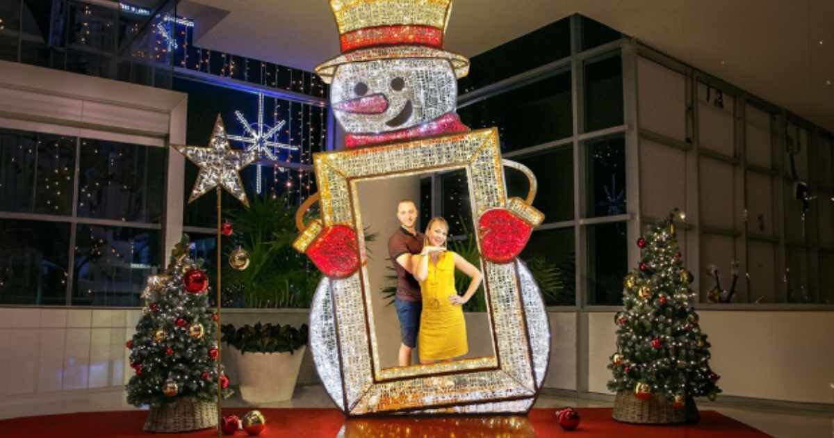 Snowman display: A light-up snowman holding a photo frame, surrounded by Christmas trees.